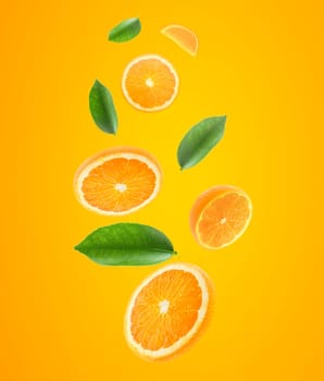 Falling juicy oranges with green leaves on orange background. Flying defocusing slices of oranges. Applicable for fruit juice advertising
