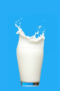 Glass of milk with splashes isolated on blue background