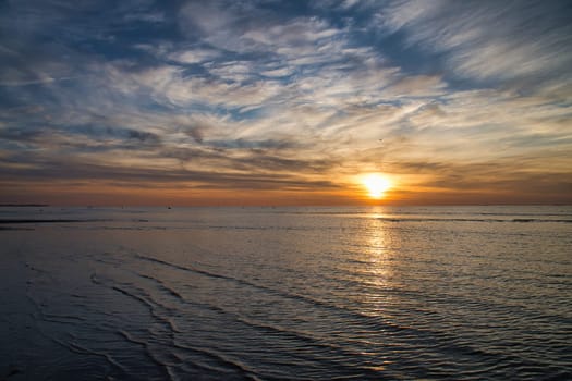 Sunset, illuminated sea. Sandy beach in the foreground. Light waves. Poel island on the Baltic Sea. Nature photo from the coast