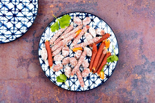 Dried organic salami sausage on a plate. Mini cabanossi. Top view.