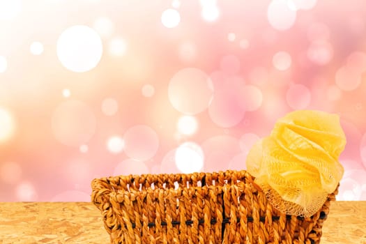 Empty wicker basket decorated with a yellow ribbon on table over abstract bright summer background. For your food and product display assembly. Copy space.