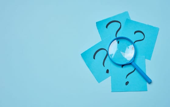 Drawn question marks on stickers and a magnifying glass, blue background. Searching for truth and answering questions