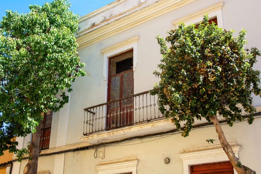 Balcony with a balcony door on an old house in Spain on the Canary Island of Gran Canaria, with trees