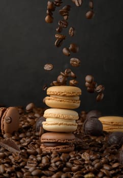 Stack of colorful macarons and flying coffee beans on a black background
