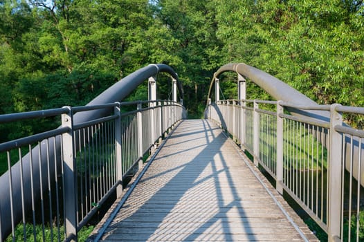 View of a metal and wooden pedestrian bridge in green nature