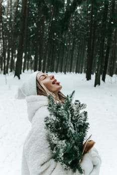 Happy young woman catching snowflakes with mouth in winter forest