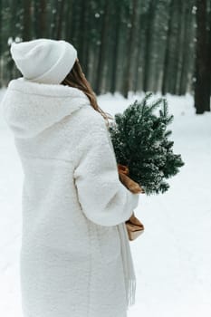 Blonde woman wears white fur coat and knitted hat posing with fir tree in winter forest, back view