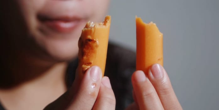 Woman eating sausage on blurred background, Street food co