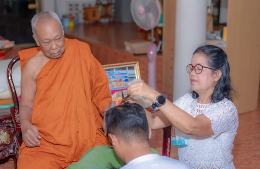Bangkok, Thailand- March 26, 2021: Ordained, Father and Mother and people join together to shave the head of a young man who is about to be ordained, According to the principles of belief in Buddhism