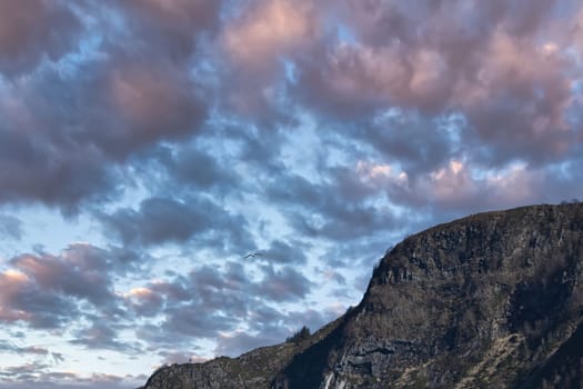Westcap in Norway. Mountain that reaches into the fjord. Cloudy sky with clouds illuminated by the sun. Landscape shot from Scandinavia