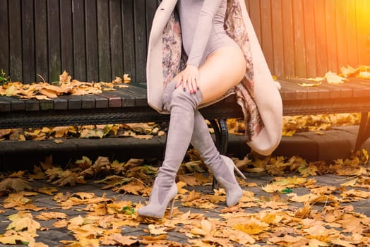 Young beautiful dark-haired woman with a slender figure posing in lingerie and a classic coat in an autumn park