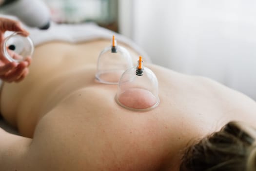 A woman does a hip massage with vacuum jar for an anti-cellulite massage.
