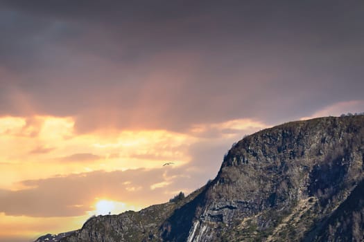 Westcap in Norway. Mountain that reaches into the fjord. Cloudy sky with clouds illuminated by the sun. Landscape shot from Scandinavia