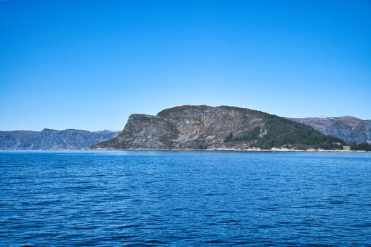 Western cap in Norway. A mountain reaching into the fjord. Blue sky. Landscape shot from Scandinavia