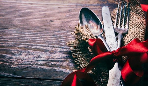 Valentines dinner background with vintage silverware and red ribbon on wooden table. Luxury restaurant menu for romantic celebration event. Valentine day dine.