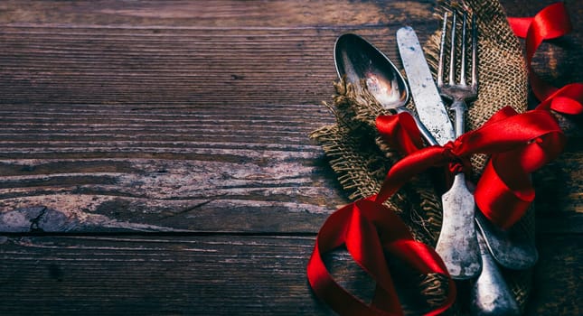 Valentines dinner background with vintage silverware and red ribbon on wooden table. Luxury restaurant menu for romantic celebration event. Valentine day dine.