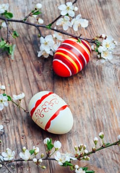 Top view of colorful painted easter eggs and cherry blossom branch decor on vintage wooden table. Traditional seasonal holiday still life from above. Easter celebrate and spring concept.