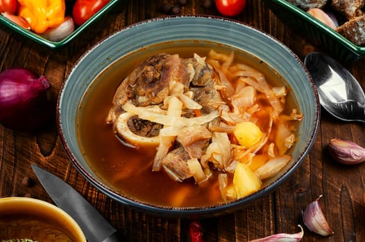 Soup with meat on old rustic wooden table. Traditional Ukrainian borscht. Food recipe.