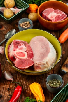 Raw piece meat and vegetables on the kitchen table. Set of ingredients for soup or borscht on old rustic wooden table.