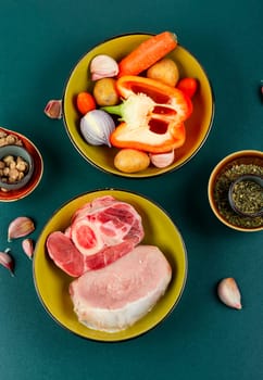 Raw piece meat and vegetables on the kitchen table. Set of ingredients for soup or borscht on old rustic wooden table.