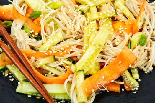 Plate with salad of enoki mushrooms and vegetables. National Chinese food. Flammulina velutipes salad. Close up.