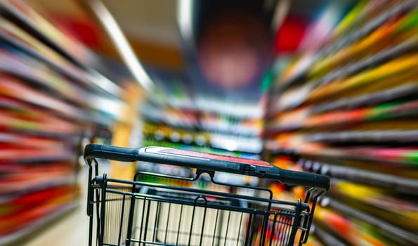 A shopping cart by a store shelf in a supermarket