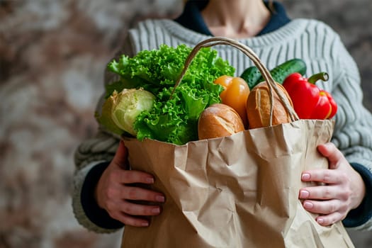 Young woman holds paper bag from supermarket with food .