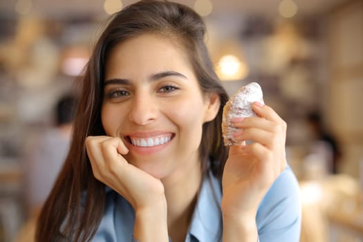 Happy woman smiling holding snack and looking at camera in a bar interior
