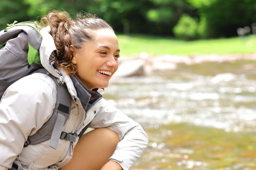 Happy hiker looks away in a riverside in the mountain