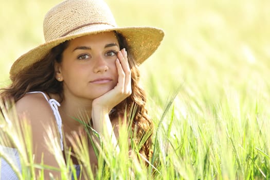 Portrait of a serious woman wearing pamela hat looking at you in a field