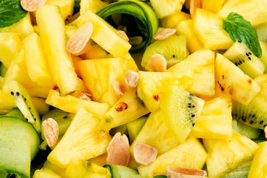 Vegan fresh pineapple and cucumber salad. Pineapple salad served on a black plate and chopstick.