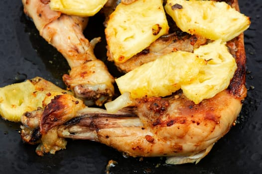 Roasted quarters chicken legs with pineapple slices. Baked chicken meat. Close up.