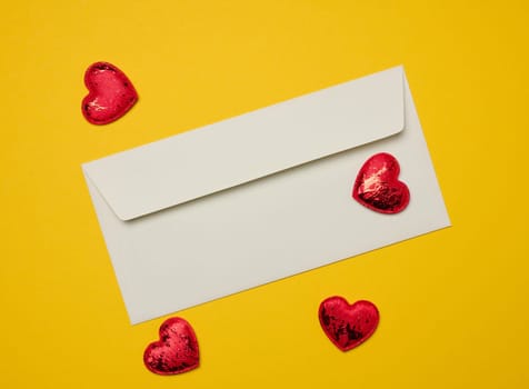 Rectangular white paper envelope and red hearts on a yellow background, holiday background