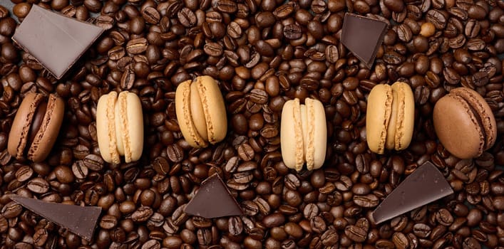Multi-colored macarons on a background of coffee beans, top view