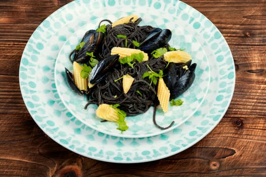 Vegan black bean pasta with mussels. Spaghetti with seafood on a concrete kitchen table.