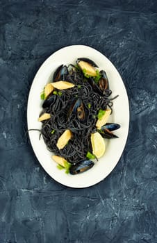 Vegan black bean pasta with mussels. Spaghetti with seafood on a concrete kitchen table.