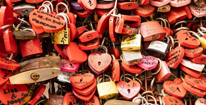 Verona, Italy - June 2022: background of heart-shaped locks on a wall, symbol of love forever