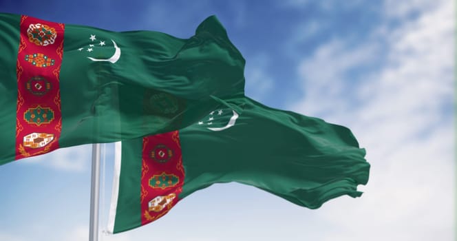 Turkmenistan national flags waving on a clear day . Green field, red vertical band, crescent moon, five stars, carpet motifs. 3d illustration render. Selective focus. Close-up. Textured background