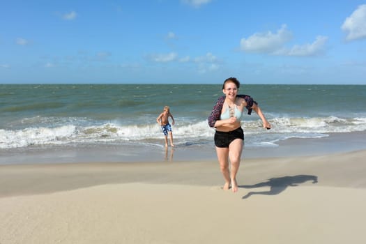 Two children have fun in the waves on the sea beach, Children run out of the water