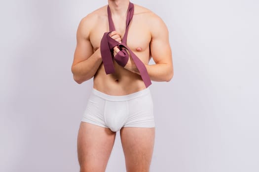Athlete with muscular body in white panties is doing physical exercises with rubber
