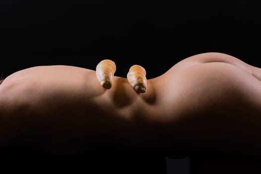 Female sensual body holding one big a white bread bun with sesame seeds, horizontal picture