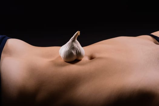 Close up of a woman belly with laying garlic, low key