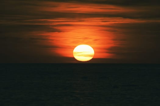 Sunset over the Baltic Sea. The red sun sinks into the sea. Evening atmosphere on the coast. Landscape photograph in northern Germany