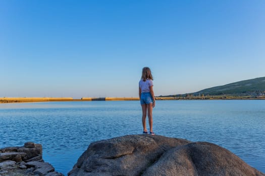 Girl tourist standing overlooking at picturesque view of the lake, in Serra da Estrela, Portugal. View from behind