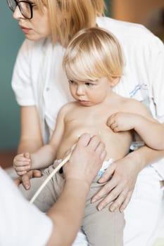 Small child being checked for heart murmur by heart ultrasound exam by cardiologist as part of regular medical checkout at pediatrician