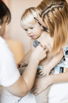 Doctor holding stethoscope and listening to child's heartbeat. Regular checkout at pediatrician at clinic or hospital. Healthcare and medical concept
