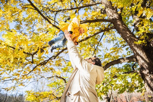 More, more,... dad, that's fun. Happy young father throws his cute little happy baby boy up in the air. Father's Day, Father and his son baby boy playing and hugging outdoors in nature in fall