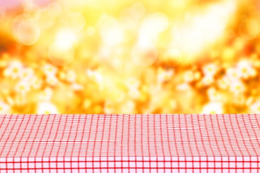Empty table product. Empty colorful checkered tablecloth over abstract blurred natural spring background texture with space for your food and product display montage.
