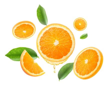 drops of juice from orange half and slices Falling juicy oranges with green leaves flying. defocusing. applicable for advertising