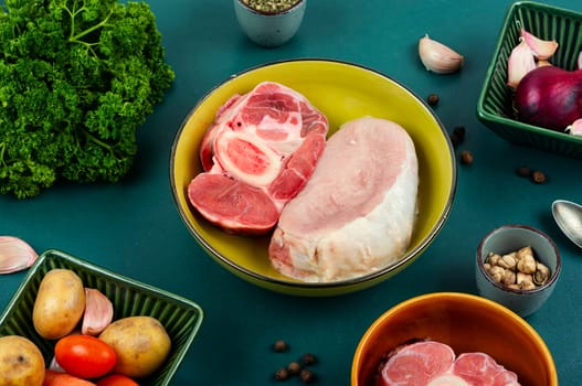 Juicy raw piece meat and vegetables on the kitchen table. Set of ingredients for soup or borscht.